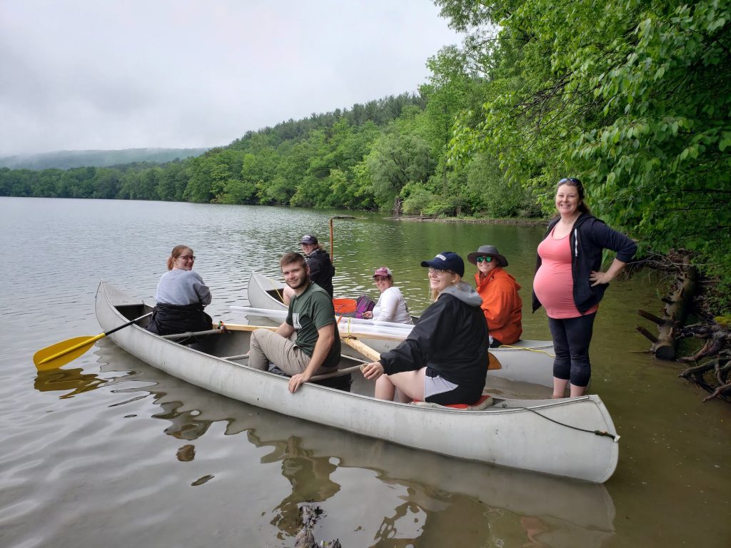 students and dr. jackie on canoe boats on a lake with oars and supplies