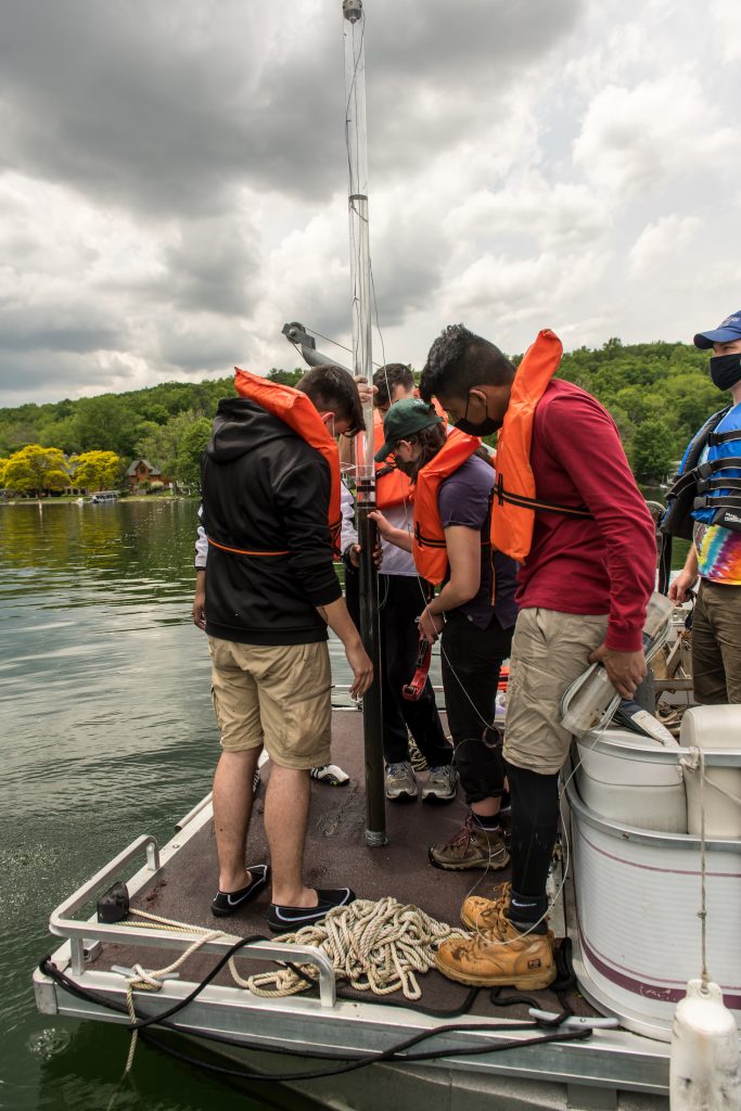 students on a boat with lifevests looking at a core