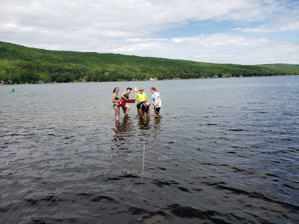 students with prof michelson in the water at collecting sediments